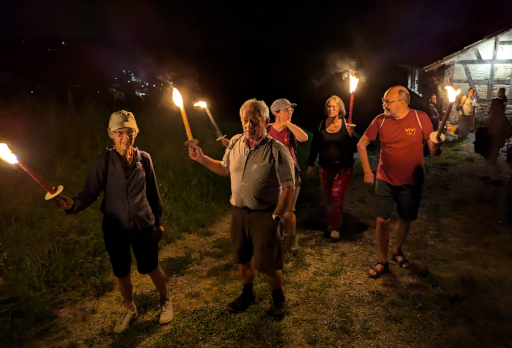 Die Gruppe mit Fackeln von vorn, wie sie von der Trotte wegspaziert.