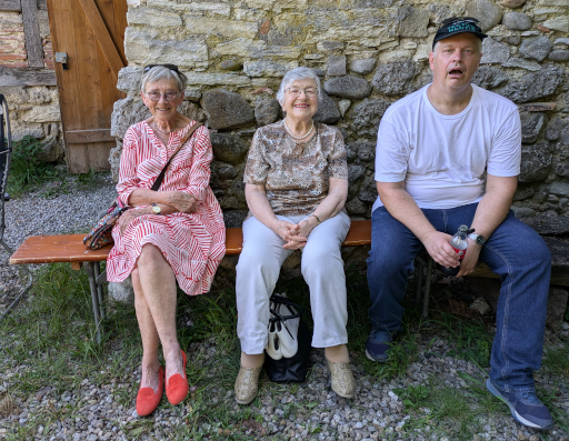 Katharina, Betty und Roland auf einer Festbank draussen vor der Trotte